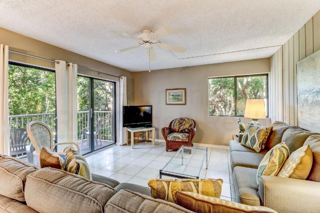 a living room with a couch and a tv at Pool View Beachwood Condo in Fernandina Beach