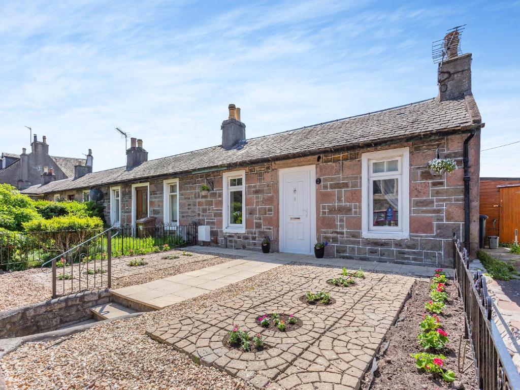 une vieille maison en briques avec une porte blanche dans l'établissement Dove Cottage, à Inverness