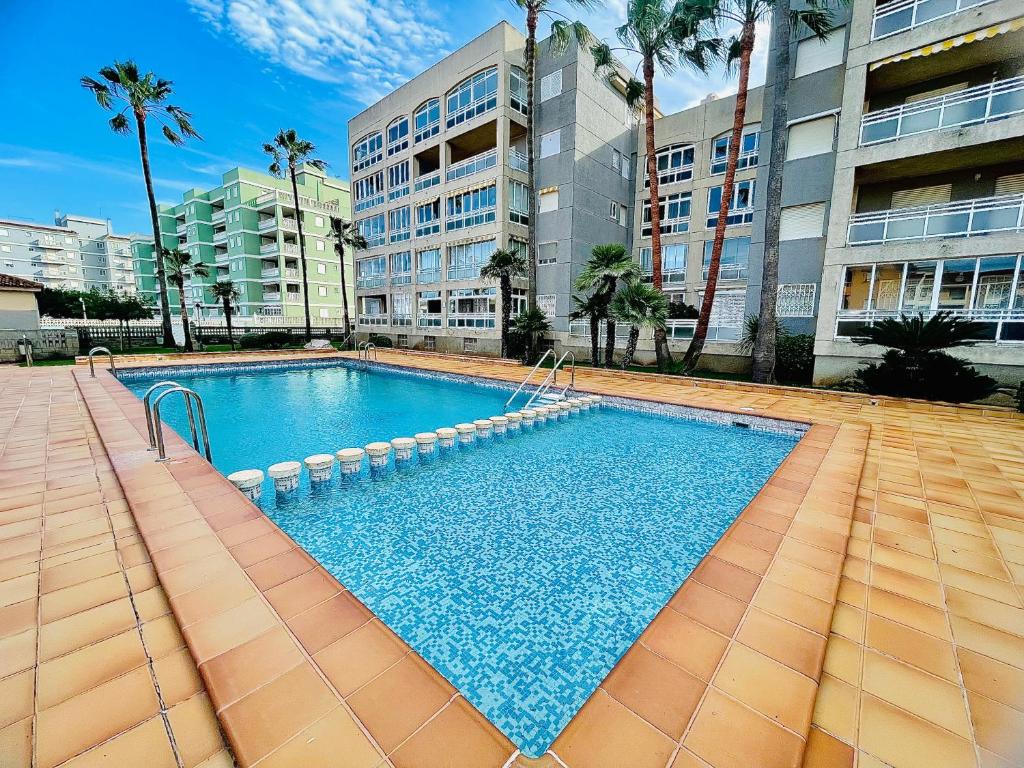 a large swimming pool in a building with palm trees at Apartamento con Piscina 3 habitaciones in Sueca