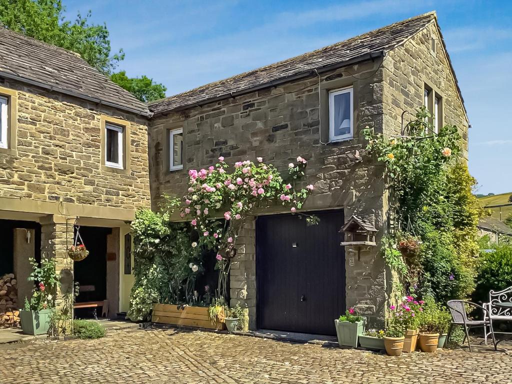 an old stone house with a black garage at Valley View in Burnsall