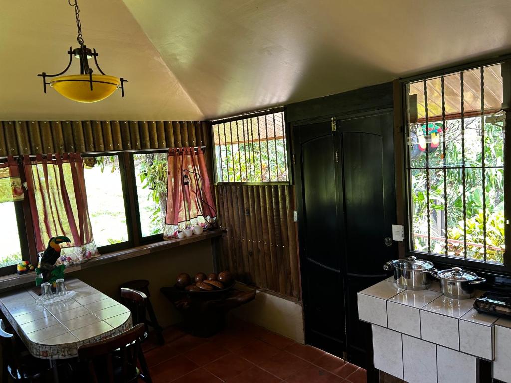 - une cuisine avec une table et quelques fenêtres dans l'établissement Cabaña en Alajuela en lugar tranquilo y con mucha naturaleza., à Tambor
