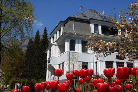 una casa blanca con tulipanes rojos delante de ella en Villa Sudrow, en Bad Reichenhall