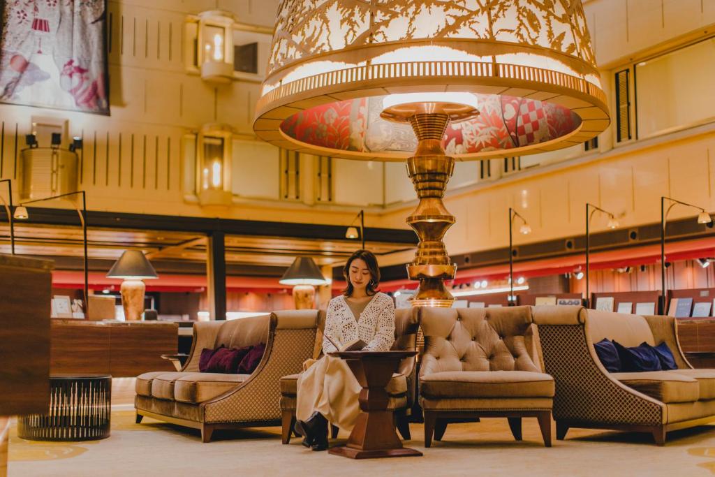 a woman standing in a lobby with chairs and a large chandelier at Kyoto Century Hotel in Kyoto