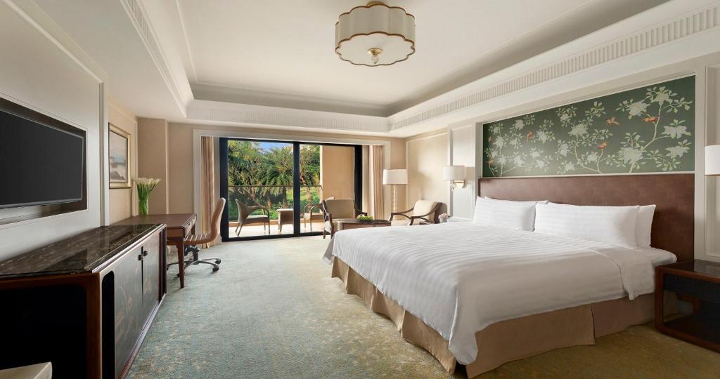 a hotel room with a large bed and a television at Grand Hotel Haikou - Managed by Accor in Haikou