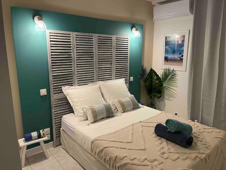 um quarto com uma cama grande e uma parede verde em La Perle Iléenne, vue imprenable sur la mer. em Les Trois-Îlets