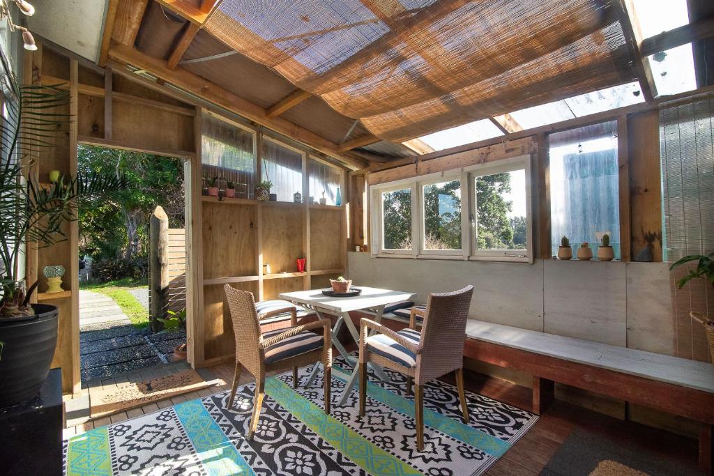 a dining room with a table and chairs on a rug at The Little House Tutukaka in Tutukaka