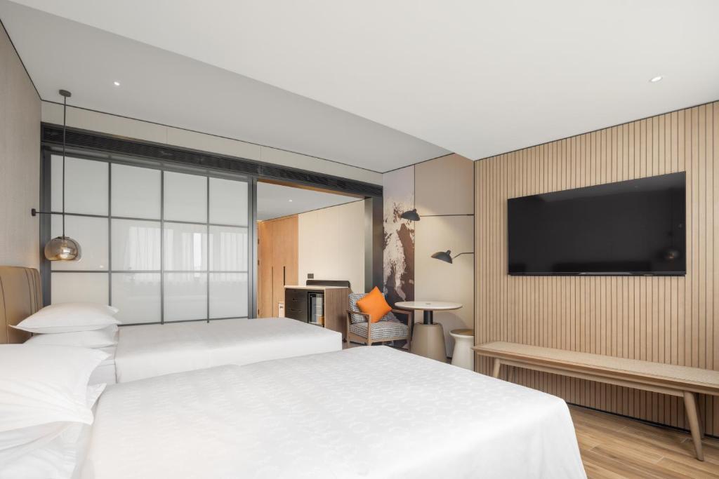 a bedroom with two beds and a flat screen tv at Sheraton Chengdu Lido Hotel in Chengdu