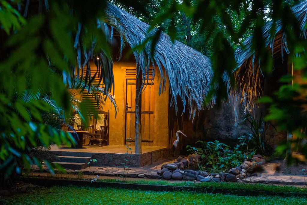 une maison avec une terrasse couverte et une croix en face de celle-ci dans l'établissement Private Organic House, à Uda Walawe