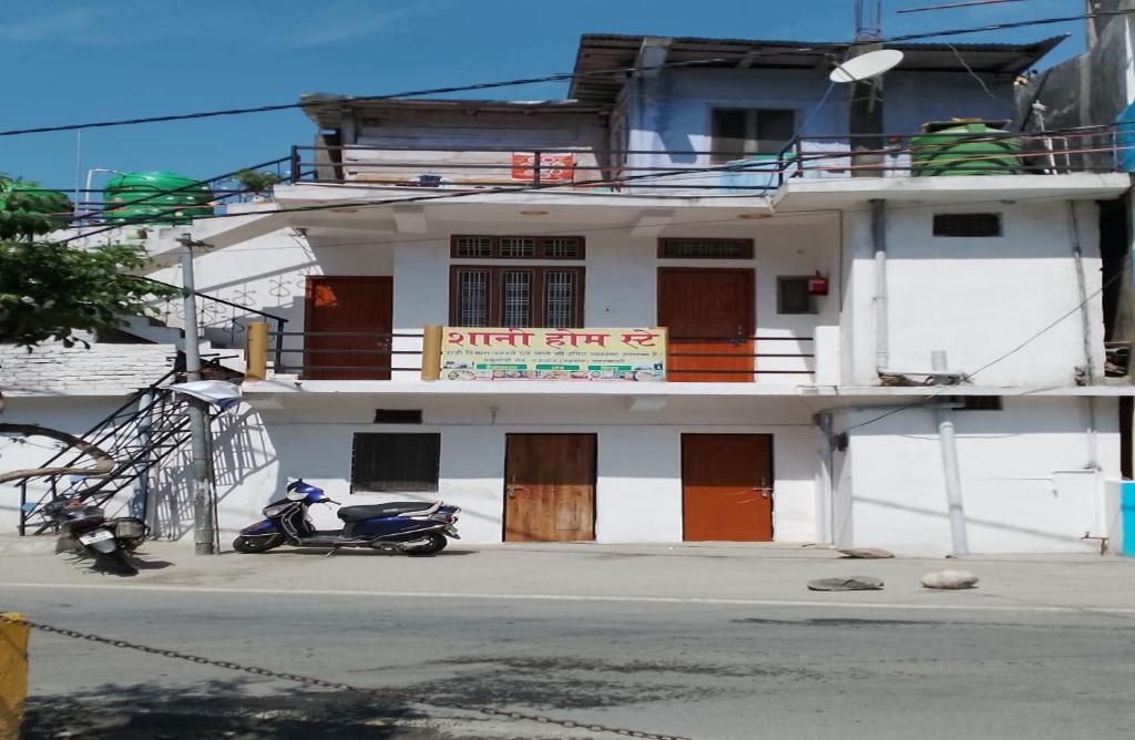 a white building with a scooter parked in front of it at Shani Homestay by StayApart in Barkot