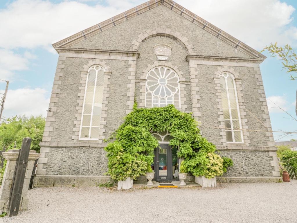 une ancienne église en pierre avec une porte noire dans l'établissement Capel Mawr, à Llanrug