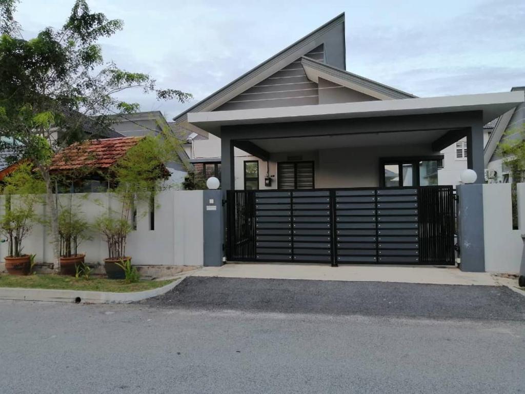 una casa con una puerta negra y una valla en Dhuha Homestay, en Kampong Kerubong