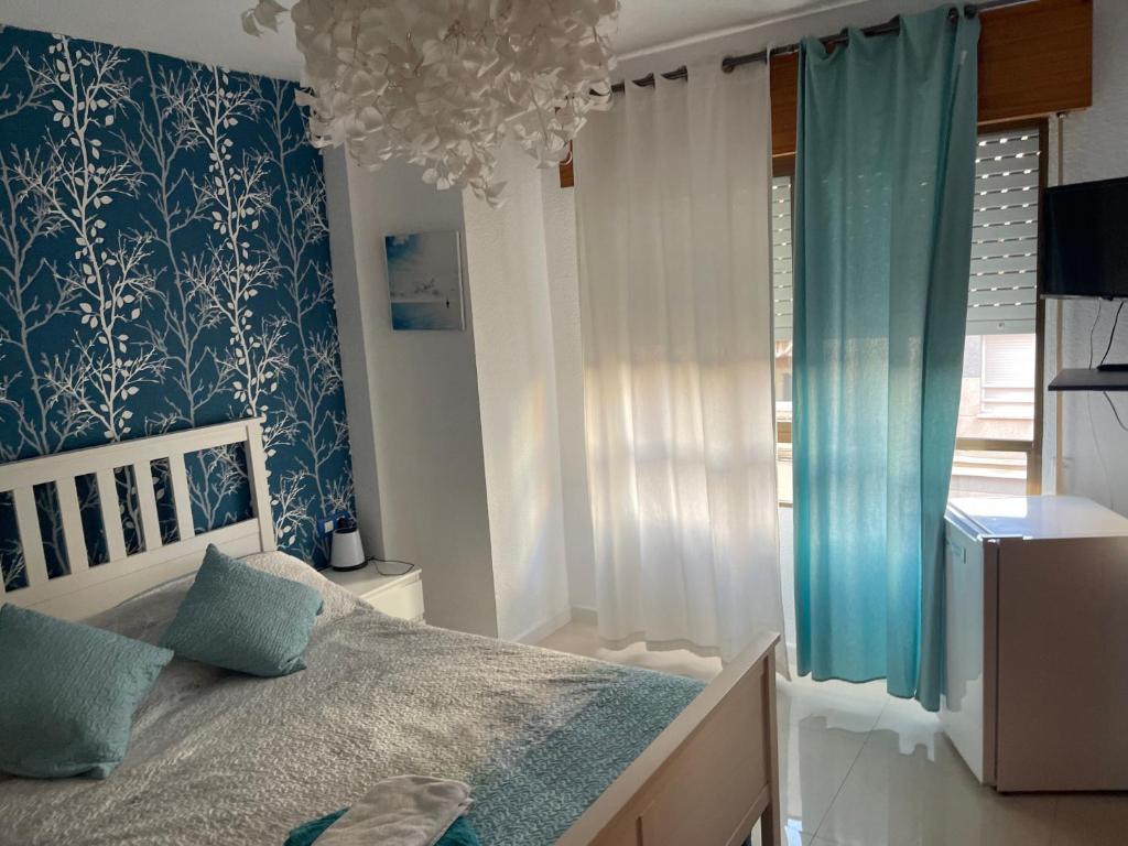 1 dormitorio con 1 cama con papel pintado azul y blanco en Casa Ojala, en Alicante