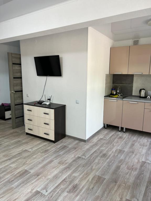 an empty room with a kitchen and a tv on a wall at Luxe-kvartira in Balqash