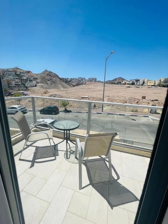 een balkon met een tafel en stoelen en uitzicht op de woestijn bij דירת סטודיו באילת in Eilat