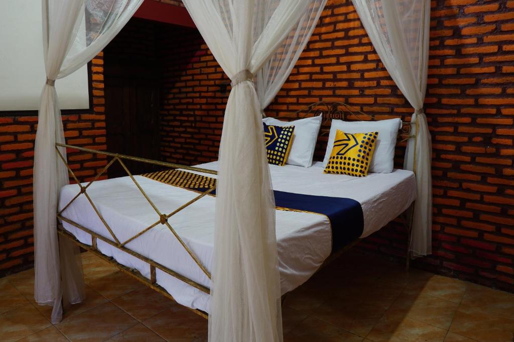 ein Schlafzimmer mit einem Himmelbett mit weißen und gelben Kissen in der Unterkunft SPOT ON 92698 Holy Homestay in Banyuwangi