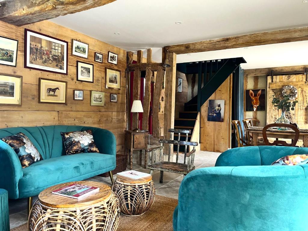 een woonkamer met blauwe meubels en houten wanden bij Gîte le Terrier in Hotot-en-Auge
