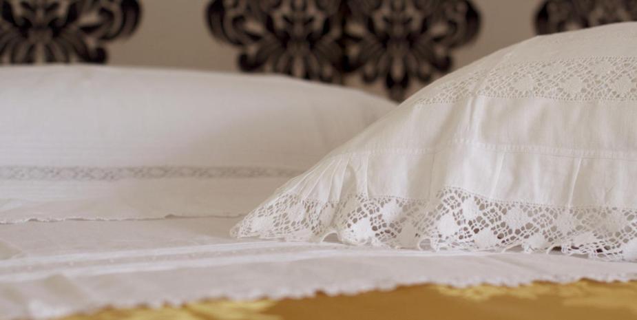 un letto con lenzuola bianche e un cuscino sopra di Locus Amoenus Luxury rooms a Terlizzi
