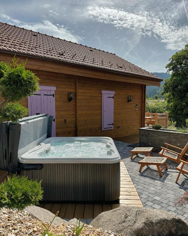 - un bain à remous sur une terrasse en face d'une maison dans l'établissement Chalet Le Montagnard SPA & SAUNA - Lits faits - Serviettes - Peignoirs - Ménage inclus, à Rochesson