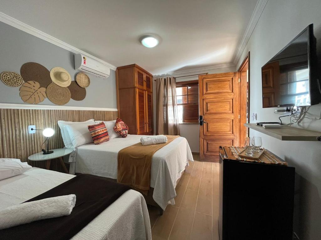 a hotel room with two beds and a television at Pousada dos Sonhos - MP in Miguel Pereira