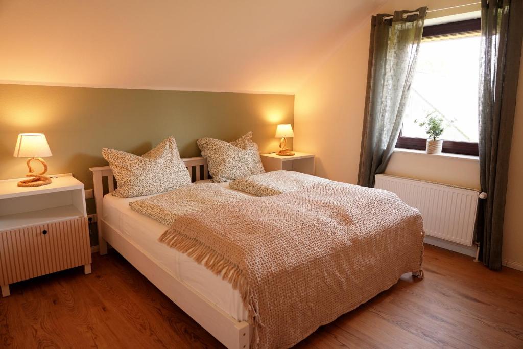 ein Schlafzimmer mit einem Bett mit zwei Nachttischen und einem Fenster in der Unterkunft FeWo Suite Spaltsberg am Binnenwasser in Neustadt in Holstein
