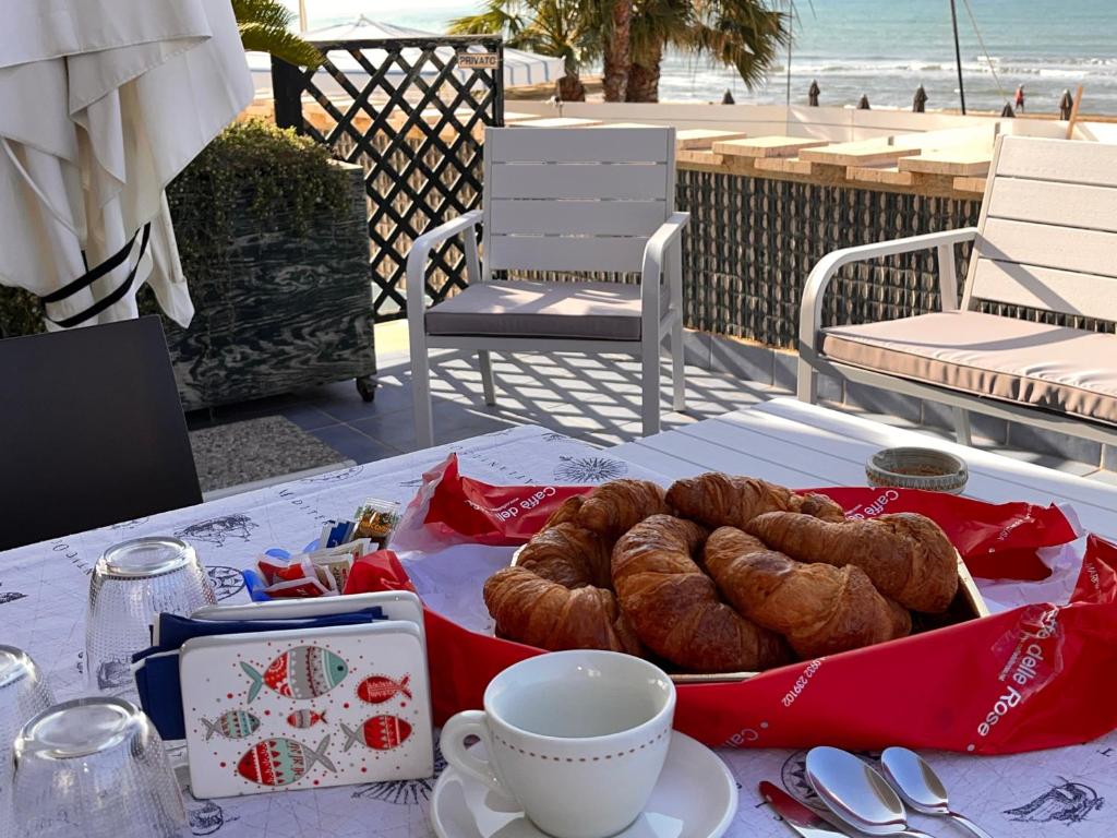 un tavolo con un cesto di croissant e una tazza di caffè di L'Onda a Marina di Ragusa