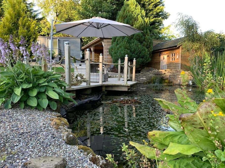 a wooden bridge over a pond with an umbrella at The Coo Shed in Balfron