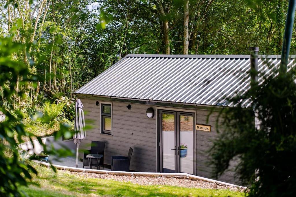 a small shed with a table and chairs in front of it at The Cabin in the Tamar Valley. in Gunnislake