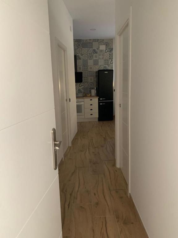 a hallway leading to a kitchen with a wooden floor at Apartamentos el Sabinar in Anchuela del Campo
