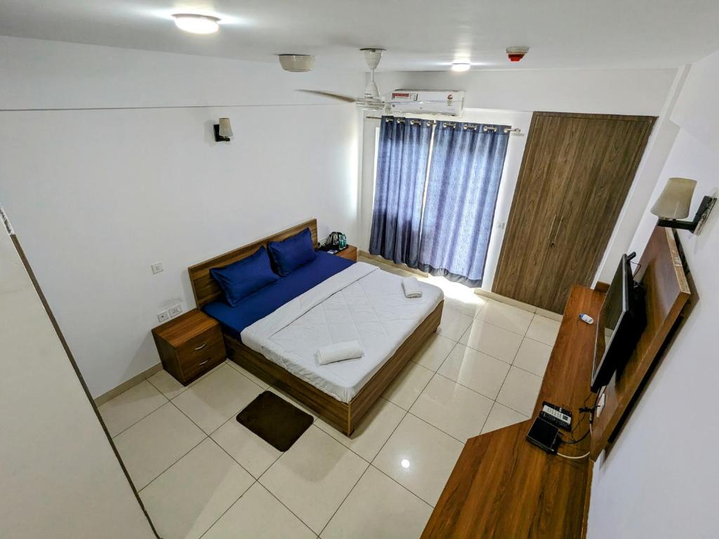 a bedroom with a blue bed and a television in it at PLUTO HOMES in Greater Noida