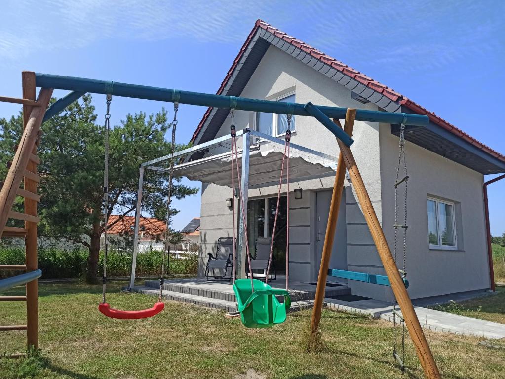 a swing set in front of a small house at Morskie Zacisze in Łeba
