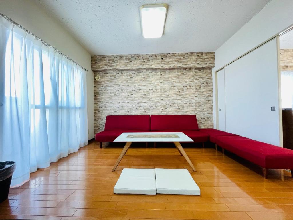 a living room with a red couch and a table at 中島9-1　NEW OPEN　景観最良の1LDK50㎡の室内空間　地下鉄駅徒歩5分以内 in Toyohira
