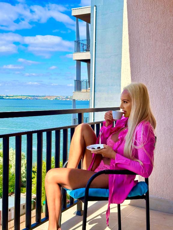 a woman sitting in a chair with a cup of coffee at Coral Residence -Mamaia Nord in Mamaia