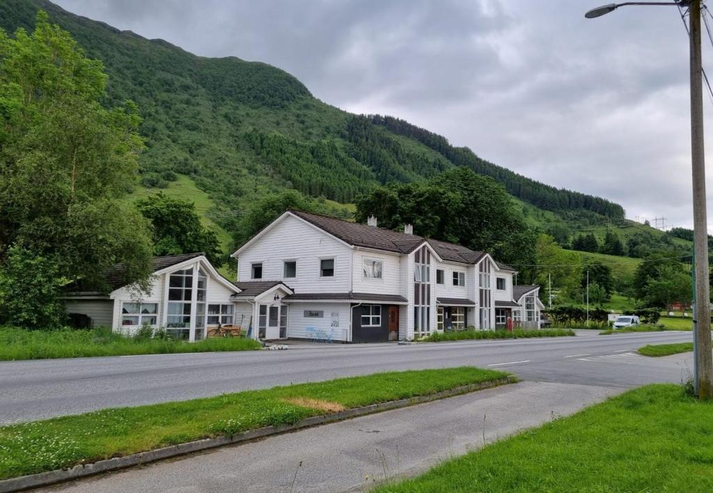 una casa al lado de una carretera con una montaña en Rosendal Apartments Motellet, en Rosendal