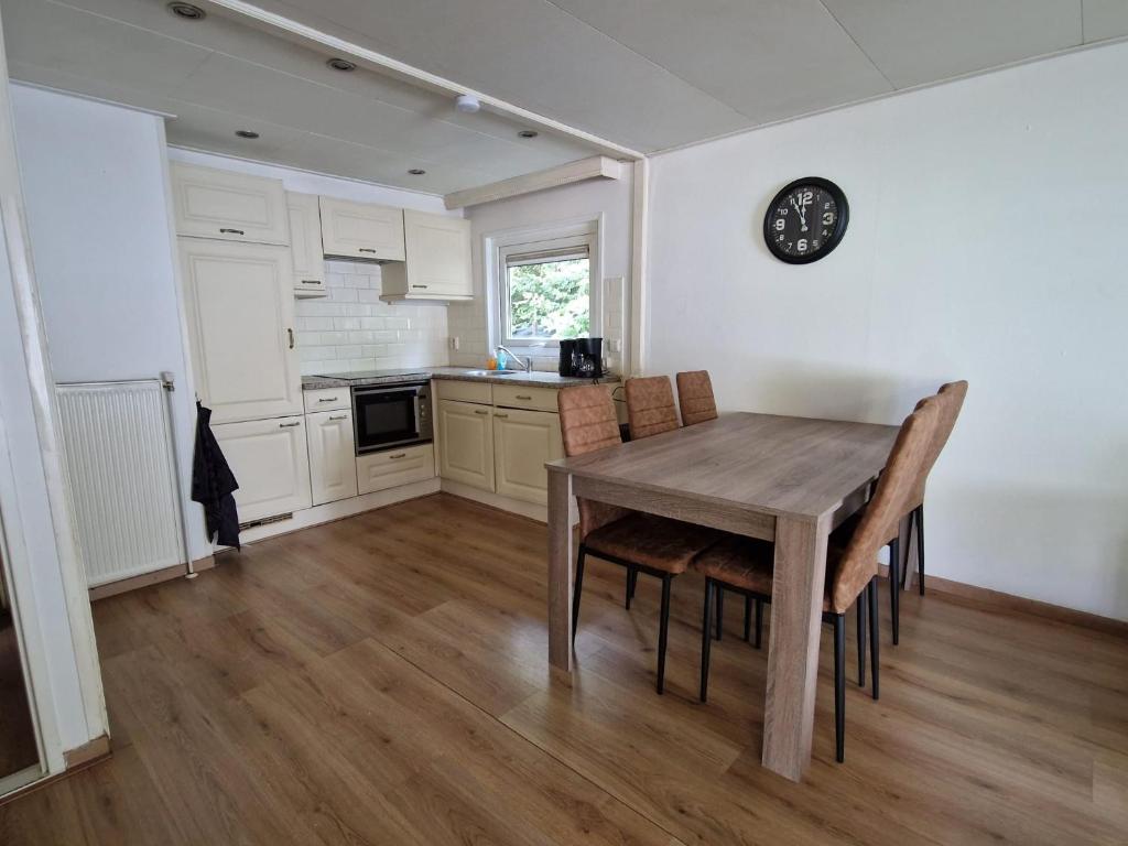 a kitchen with a table and chairs and a clock on the wall at Stacaravan Q10 Marina Beach in Hoek