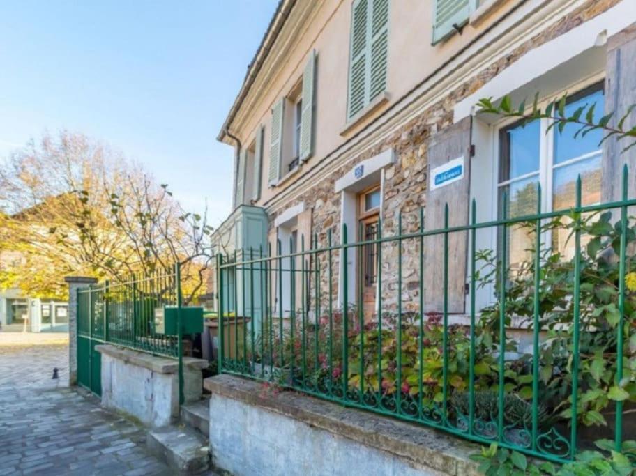 a green fence in front of a building at L' Eglise - 2 pièces avec balcon au dernier étage vue Paris in Saint-Prix