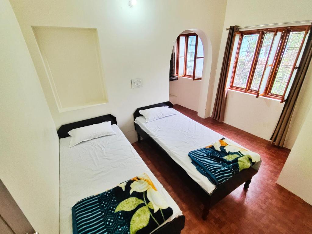 two beds in a room with two windows at Alaknanda Homestay in Karnaprayāg