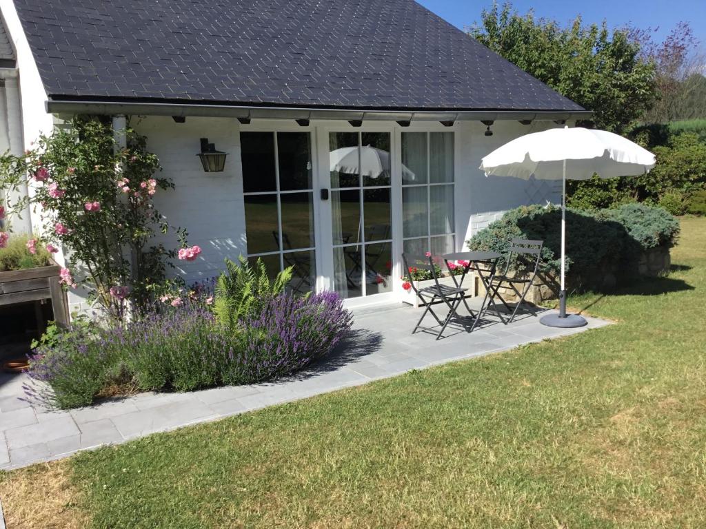 un patio con sombrilla, mesa y sillas en Clair Matin, en Malmedy