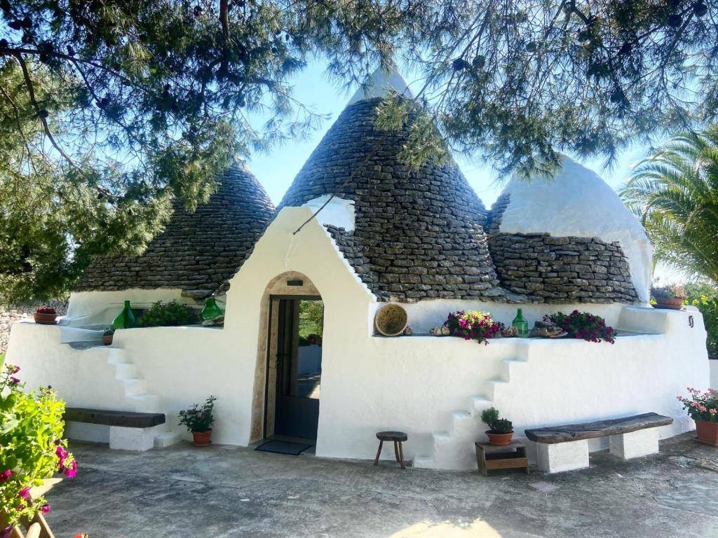 une petite maison blanche avec un grand toit dans l'établissement Trullo Le radici del Pino, à Martina Franca
