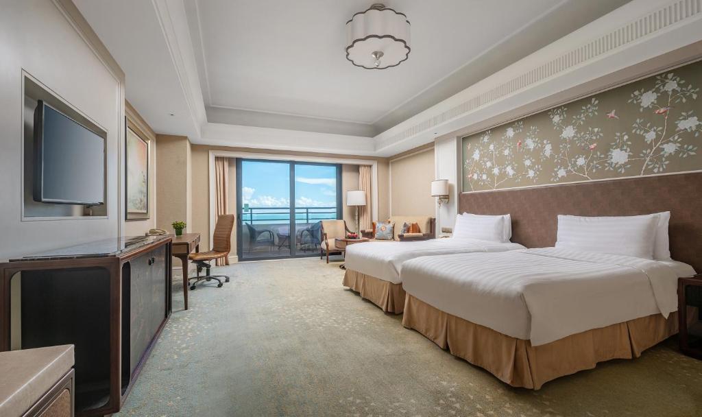 a hotel room with two beds and a flat screen tv at Grand Hotel Haikou - Managed by Accor in Haikou