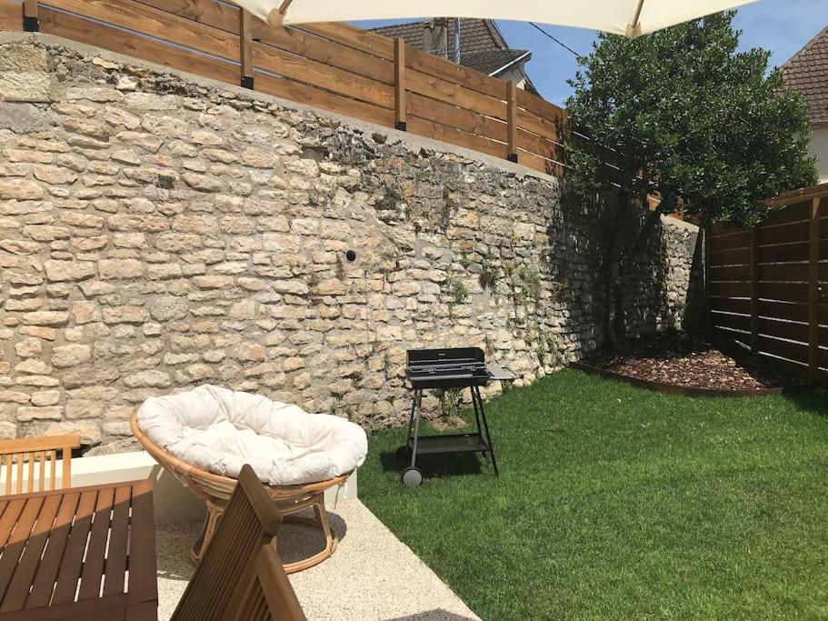 un patio trasero con una pared de piedra, una silla y una parrilla en Maison familiale au cœur du Lot en Lanzac