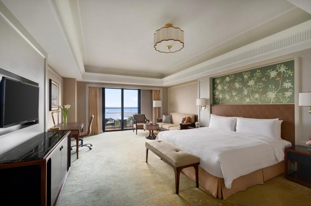 ein Hotelzimmer mit einem großen Bett und einem TV in der Unterkunft Grand Hotel Haikou - Managed by Accor in Haikou
