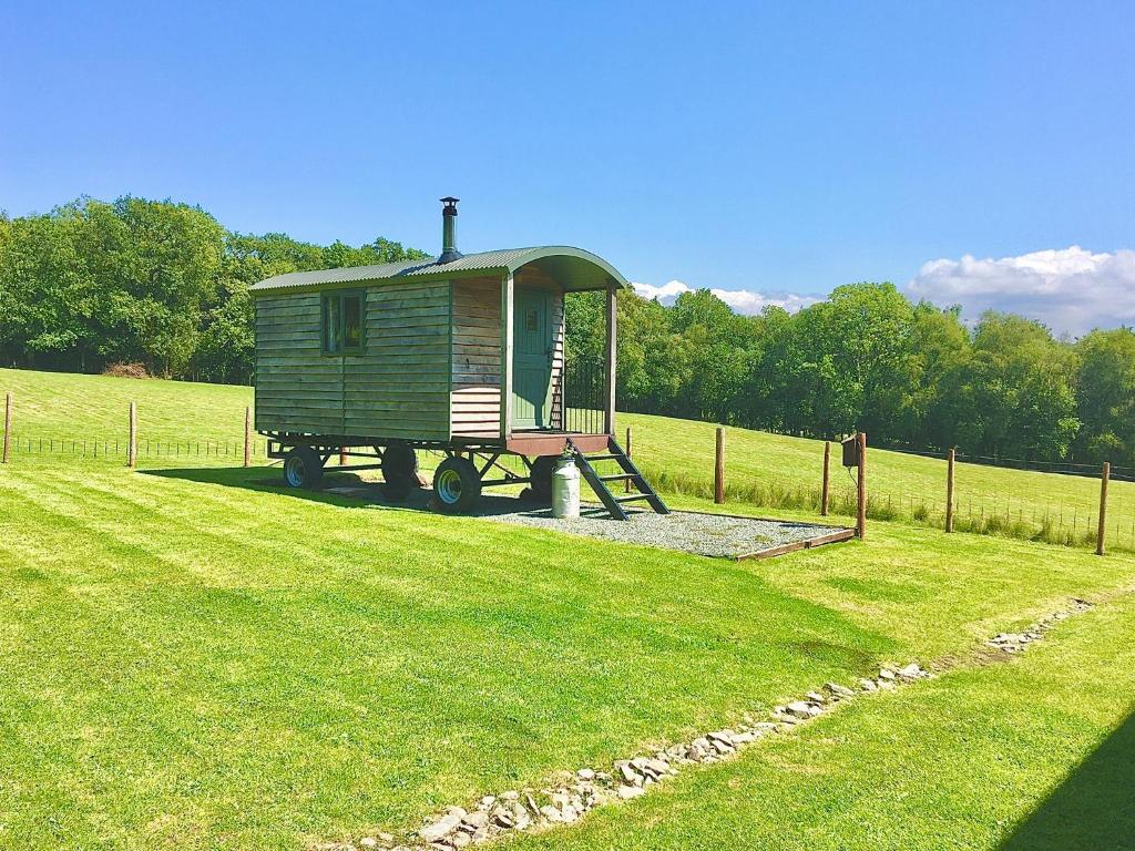 a tiny house sitting in the middle of a field at Foxgloves and Fairytales Hut with Hot Tub in Llanwrda