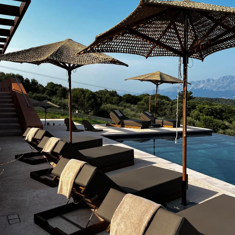 a group of lounge chairs and umbrellas next to a pool at Mirazur in Meganisi