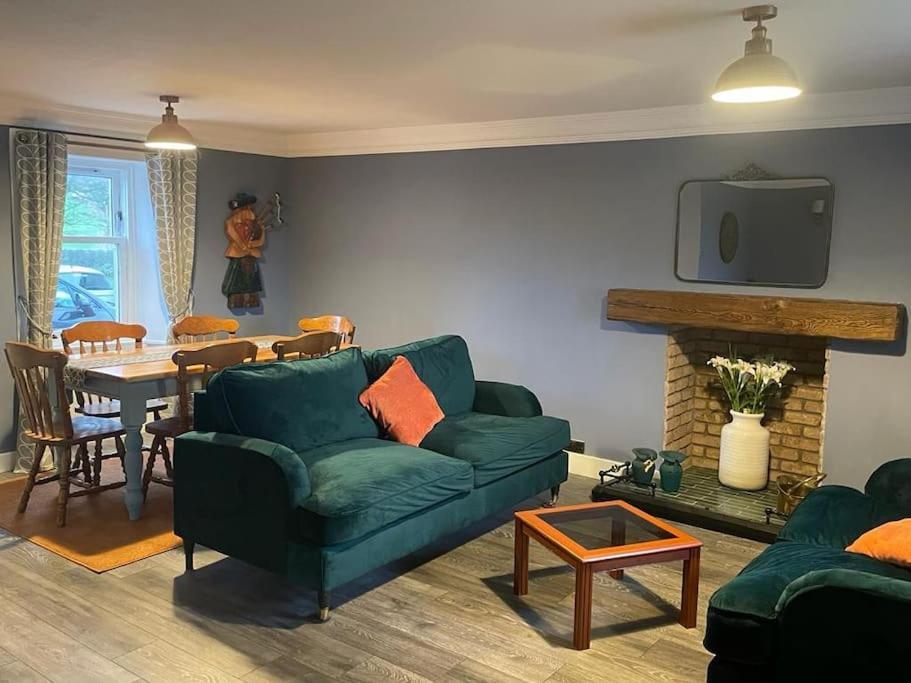 ein Wohnzimmer mit einem grünen Sofa und einem Tisch in der Unterkunft Southend, Mull of Kintyre, Campbeltown in Campbeltown