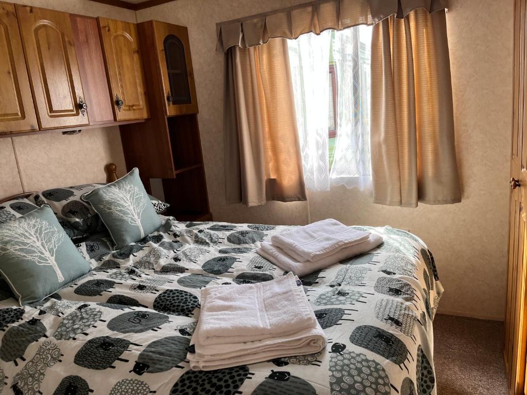 una camera da letto con un letto e asciugamani di Cosy country style static holiday home ad Aberystwyth