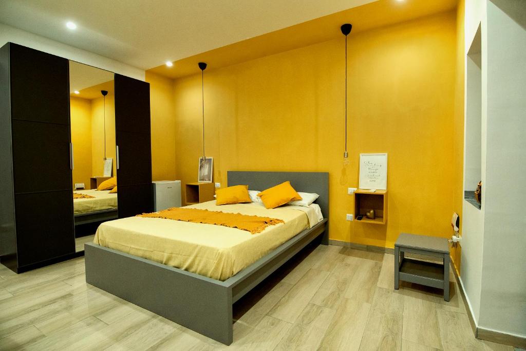 - une chambre avec un grand lit aux murs jaunes dans l'établissement Domus Martì, à Formia
