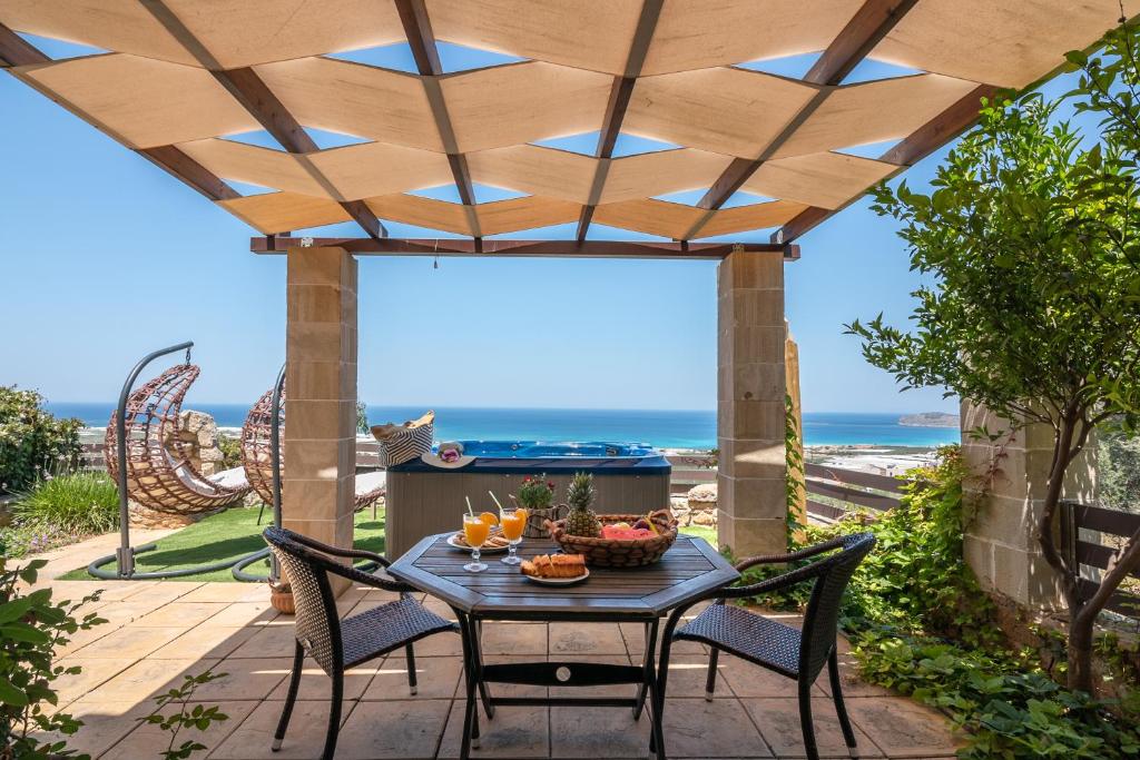 a patio with a table and chairs with the ocean in the background at The Stonemade Houses in Falasarna