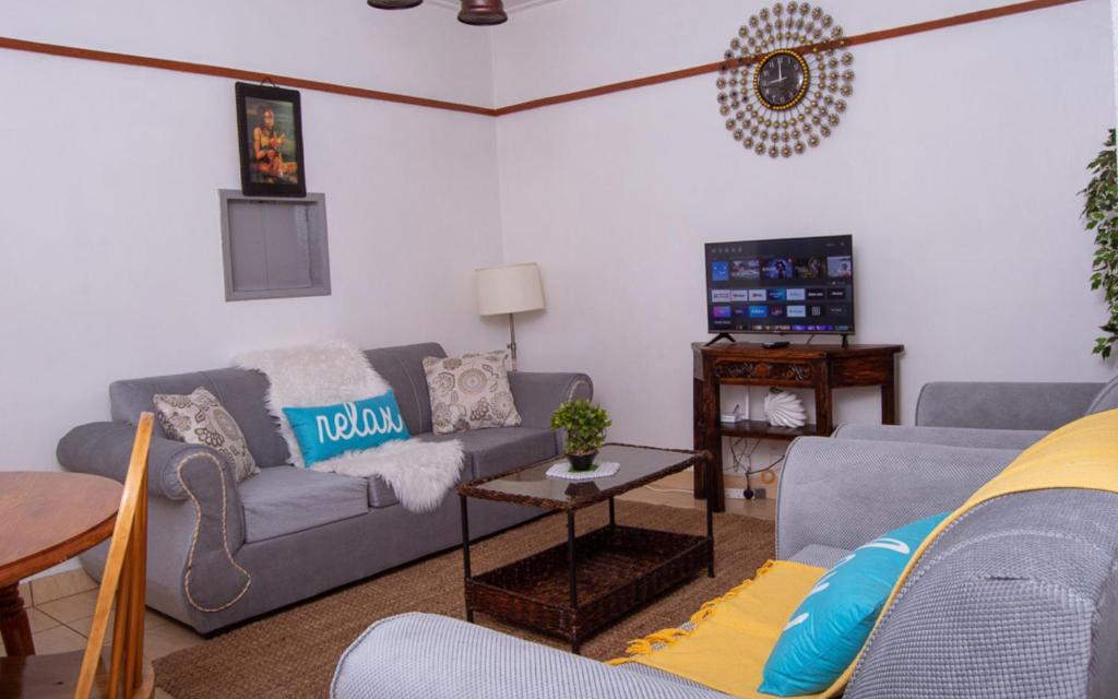 uma sala de estar com dois sofás e uma televisão em Elegant Touch Home - 2 Bedroom House in Karen em Nairobi