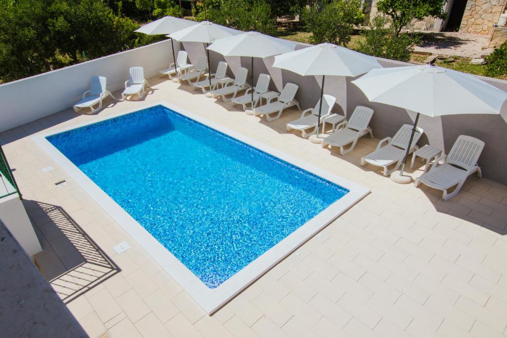 an overhead view of a swimming pool with chairs and umbrellas at Apartments M in Seget Vranjica