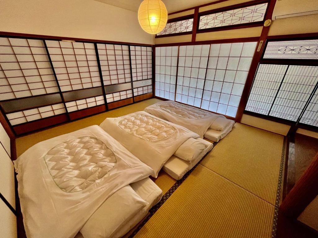 2 camas en una habitación con ventanas en オオヤシロSTAY旅音 en Izumo